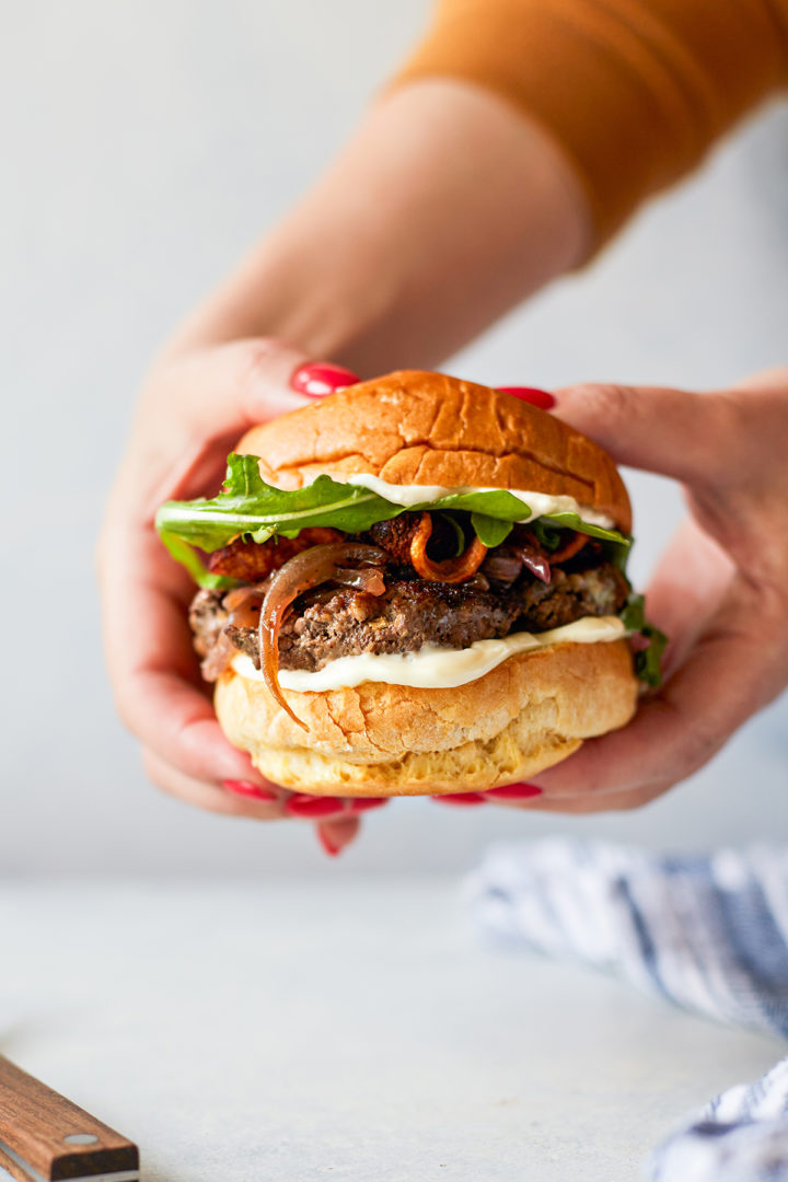 woman holding a bacon and blue cheese stuffed burger