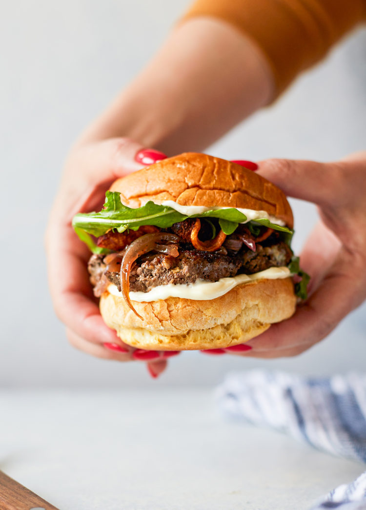 woman holding a bacon and blue cheese stuffed burger