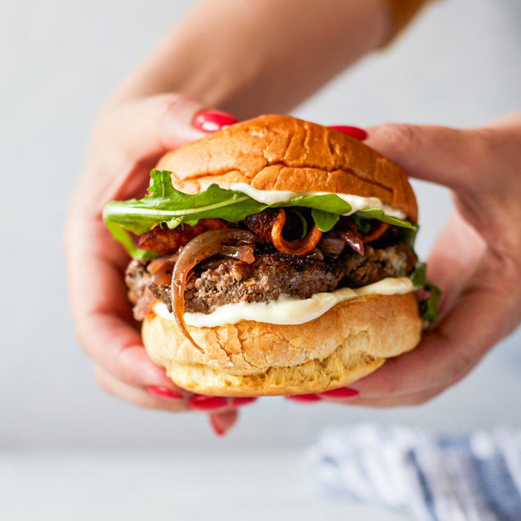 woman holding a bacon and blue cheese stuffed burger