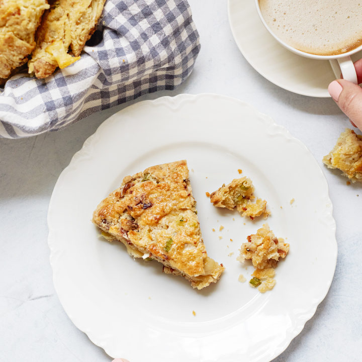 woman holding a plate with a cheese and bacon scone