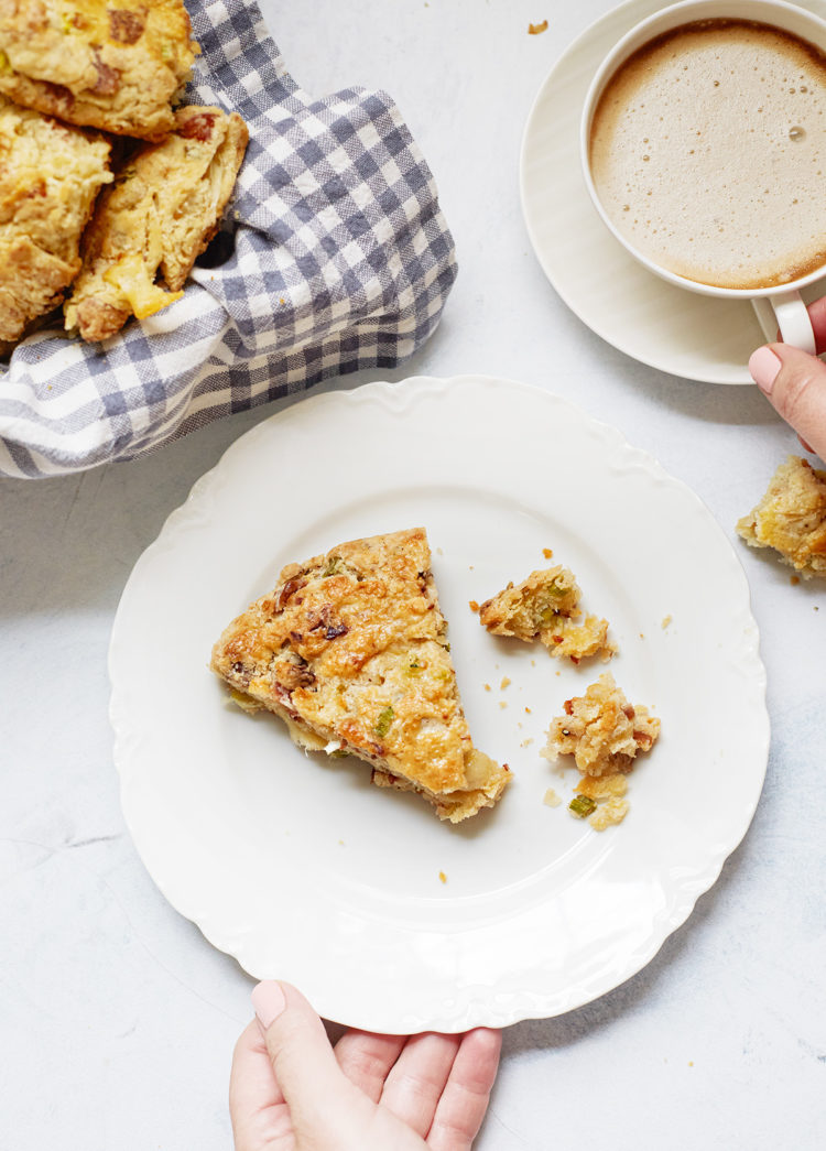 woman holding a plate with a cheese and bacon scone