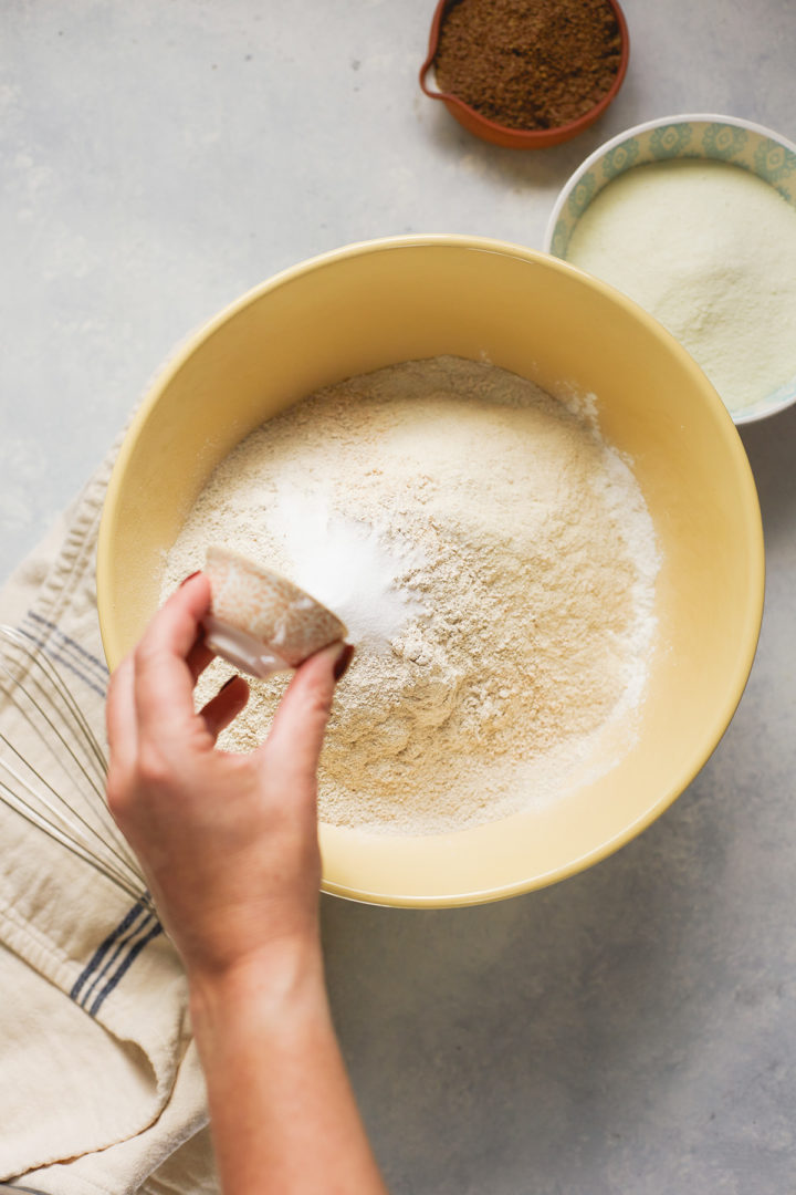 woman adding salt to a bowl with pancake ingredients