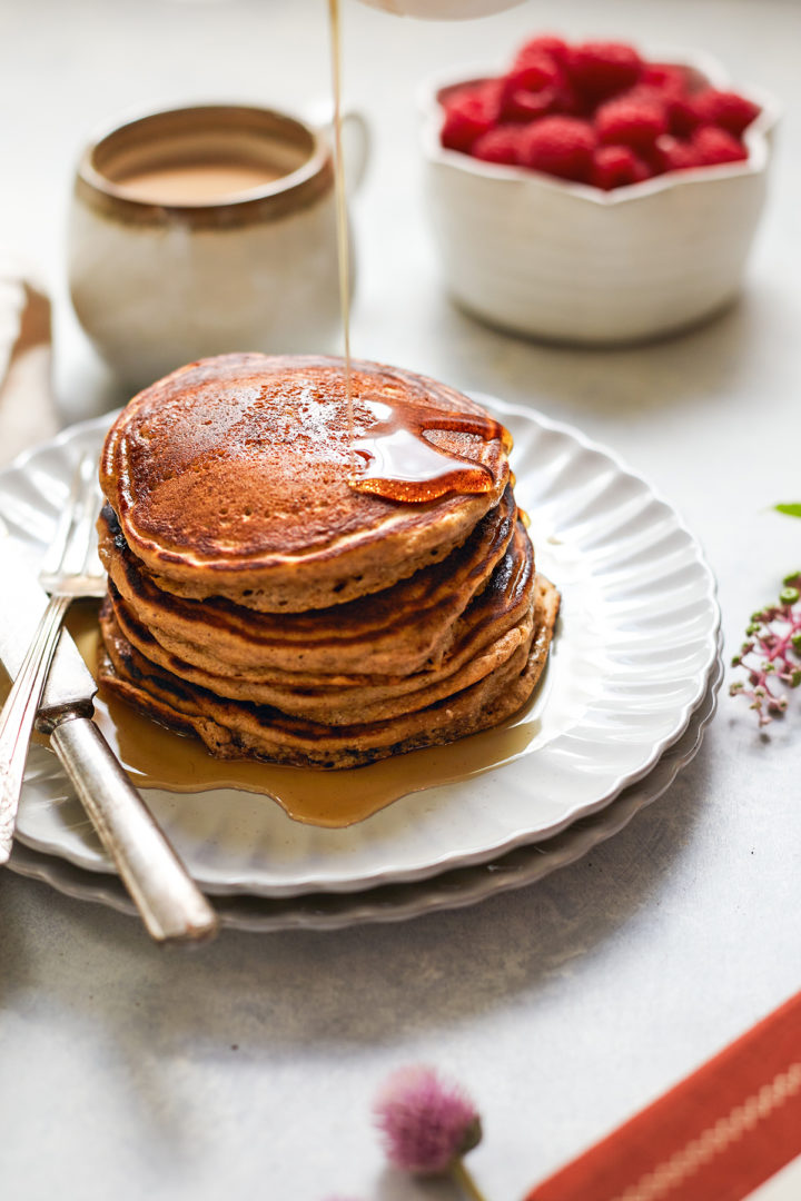 syrup drizzling over a stack of multigrain pancakes