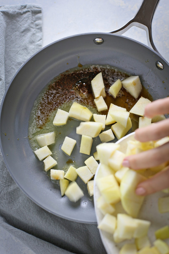 woman adding chopped pears to a pan