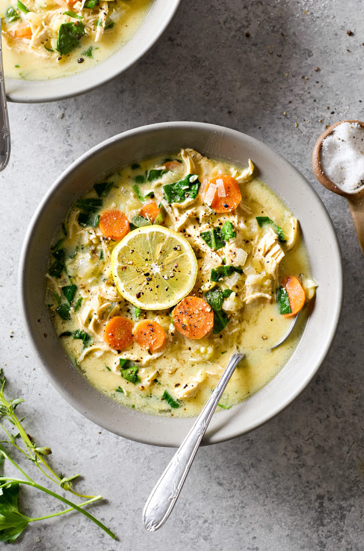 A bowl of chicken spinach orzo soup with a spoon ready to dig in.
