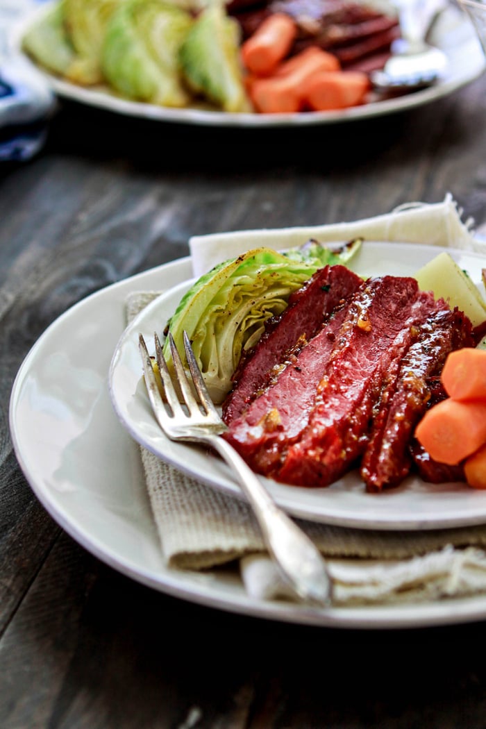 slices of homemade corned beef topped with glaze on plate with veggies