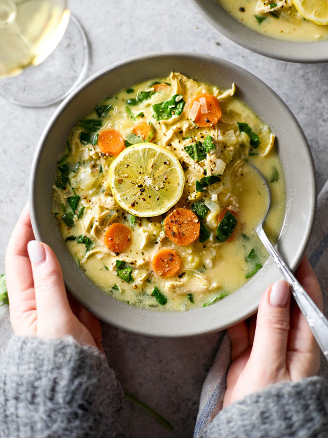 woman holding a bowl of lemon chicken orzo soup with spinach