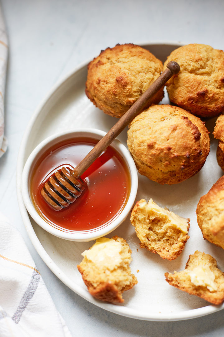 cornbread honey muffins on a plate with a bowl of honey