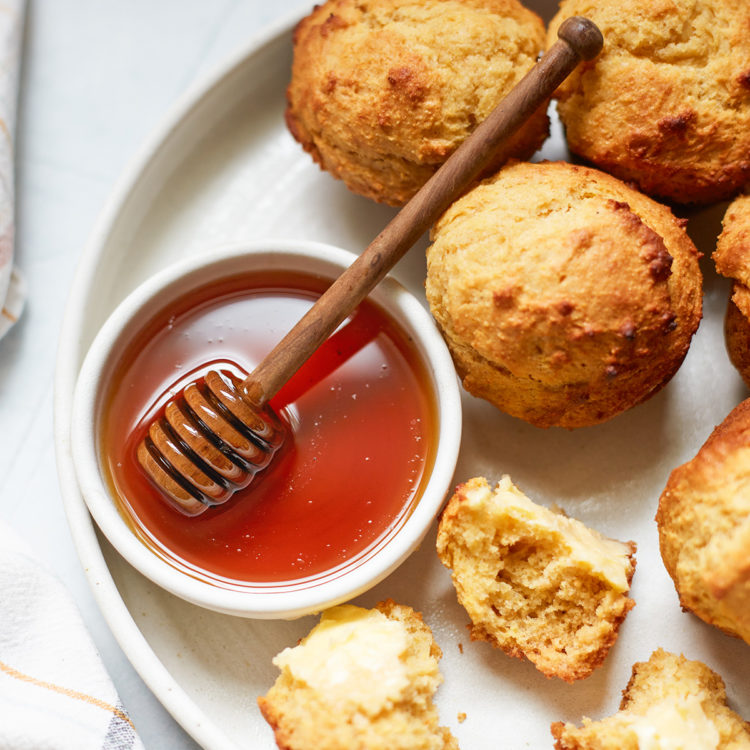 cornbread honey muffins on a plate with a bowl of honey