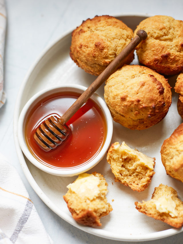 cornbread honey muffins on a plate with a bowl of honey