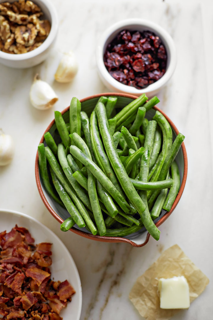 overhead photo of ingredients needed to make cranberry green beans arranged on a marble counter