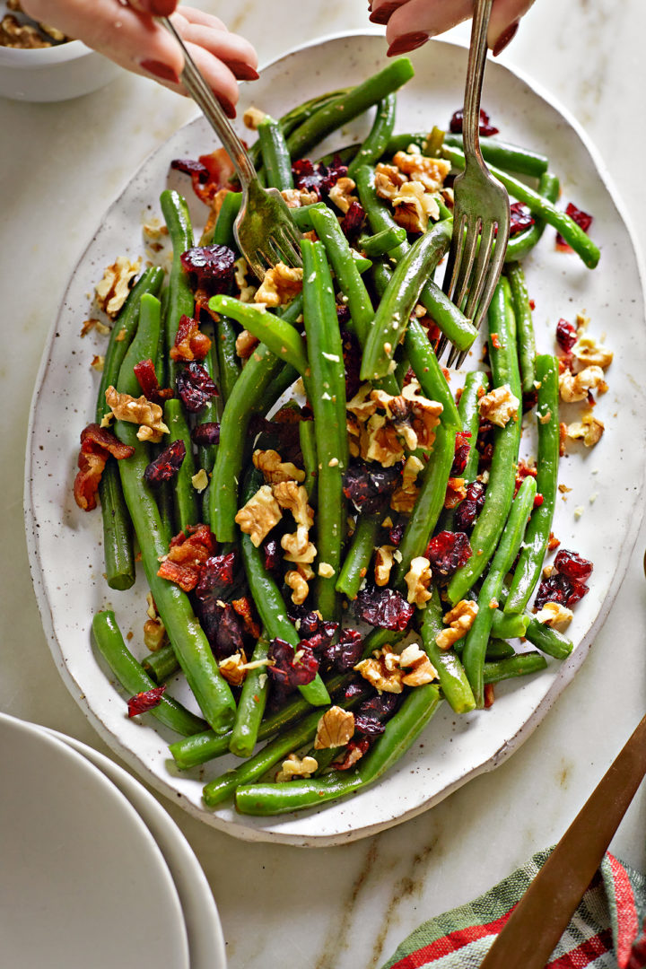 woman serving green beans with cranberries