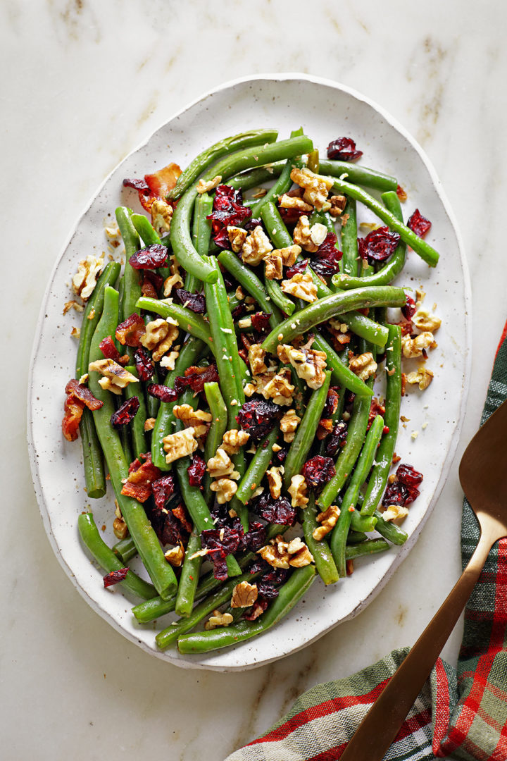 overhead photo of green beans with bacon and cranberries on a serving platter