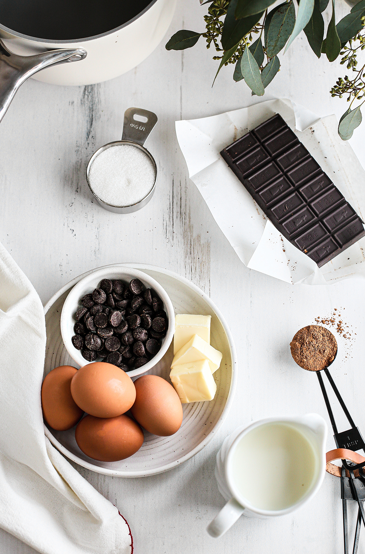 chocolate chips and a dark chocolate dark chocolate bar arranged on a white wooden table