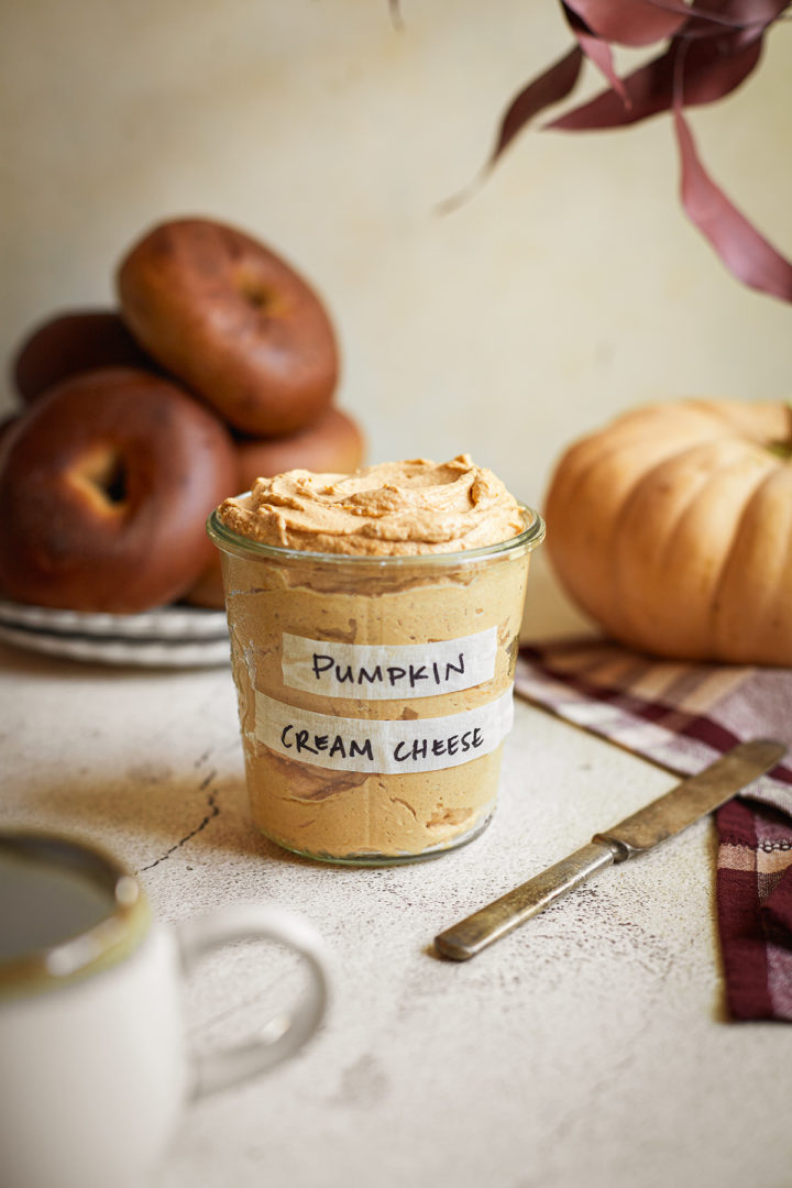 jar of pumpkin spice cream cheese next to a plate of bagels