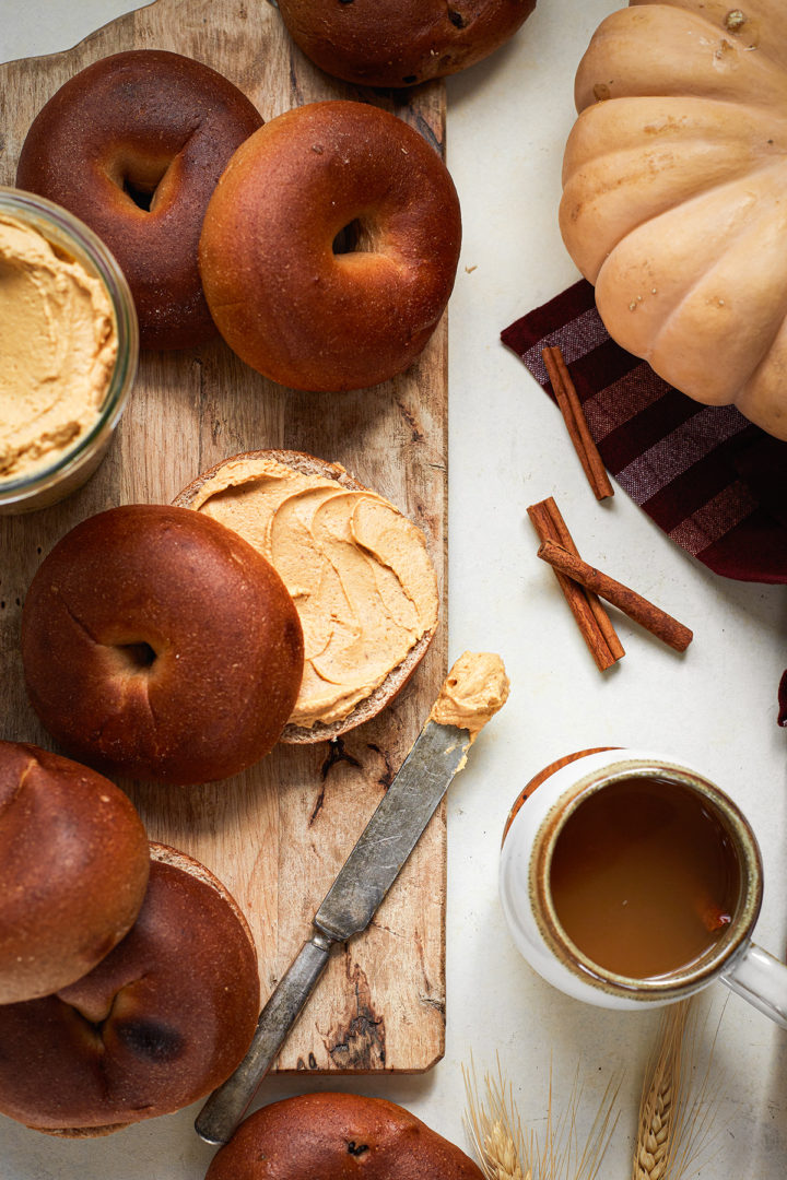 bagels with pumpkin cream cheese on a wooden cutting board