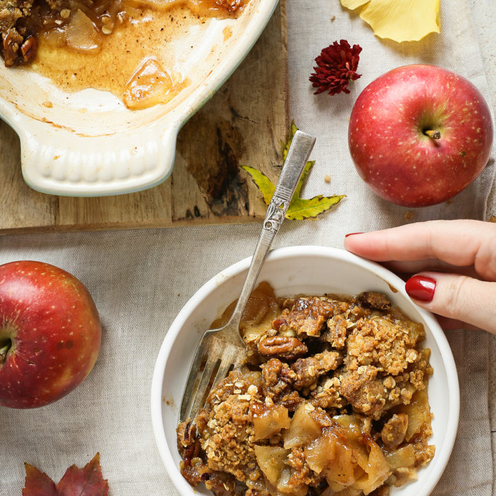 woman holding a bowl of bourbon apple crisp on a thanksgiving table