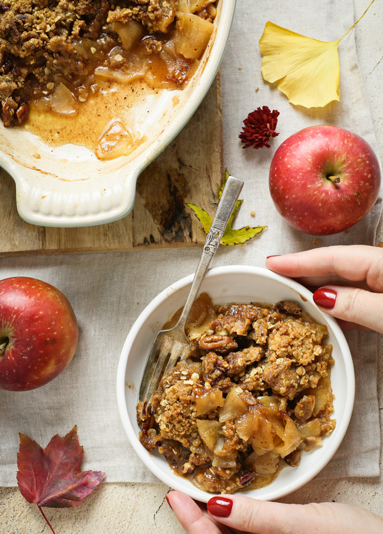 woman holding a bowl of bourbon apple crisp on a thanksgiving table