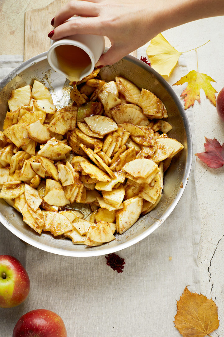 woman adding bourbon to apple crisp filling