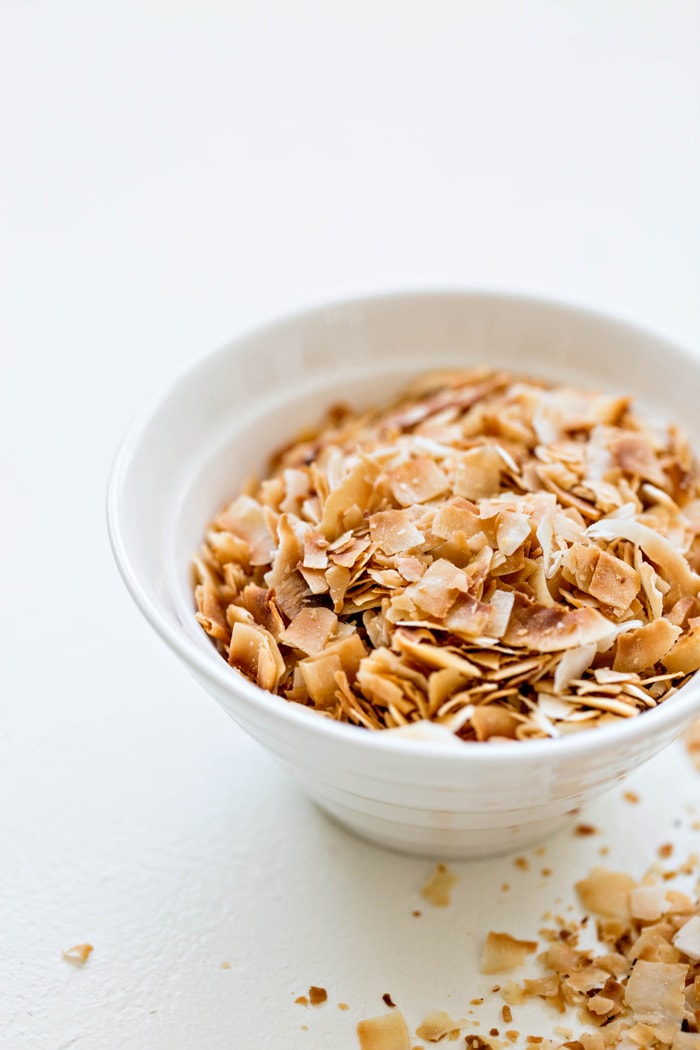 a white bowl containing toasted coconut for use in this pineapple quinoa salad recipe