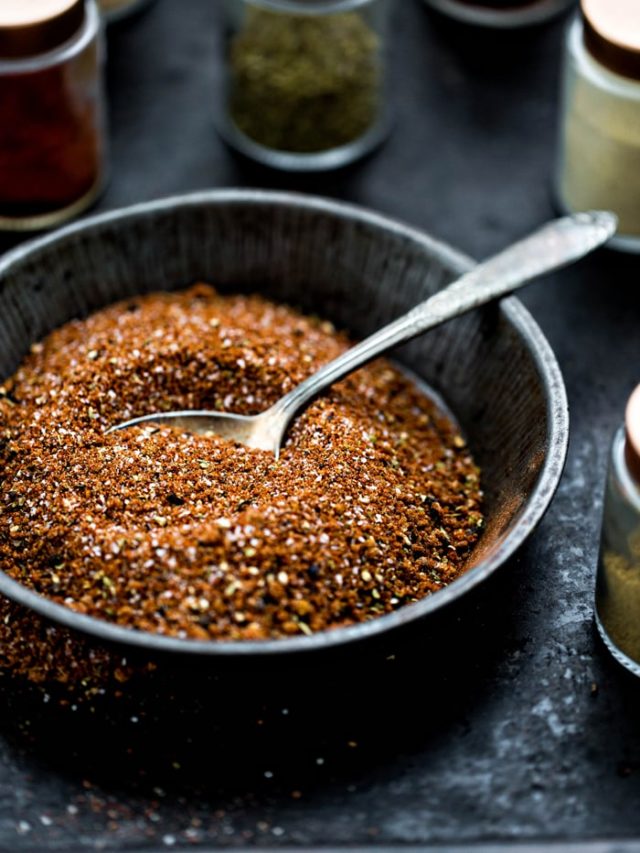 bowl of pork rub spice blend surrounded by spice jars