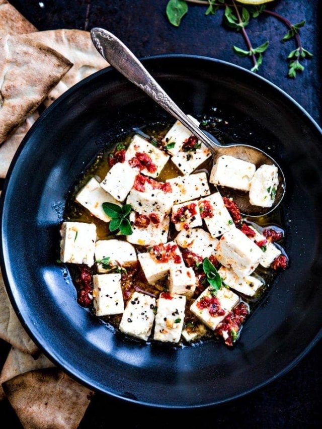 black bowl with marinated feta surrounded by pita chips