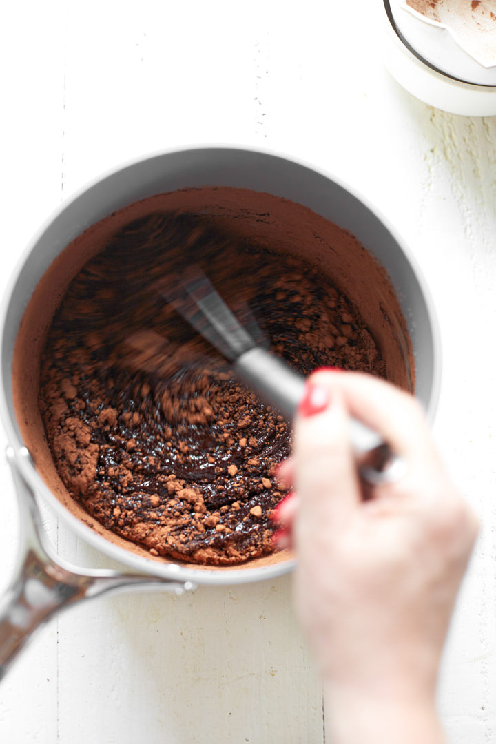 Cocoa powder being mixed into the melted butter and sugar mixture for brownie batter.