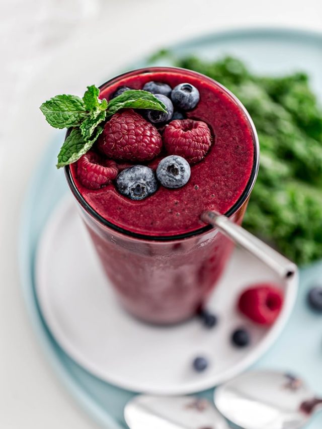 glass with berry mango kale smoothie and straw