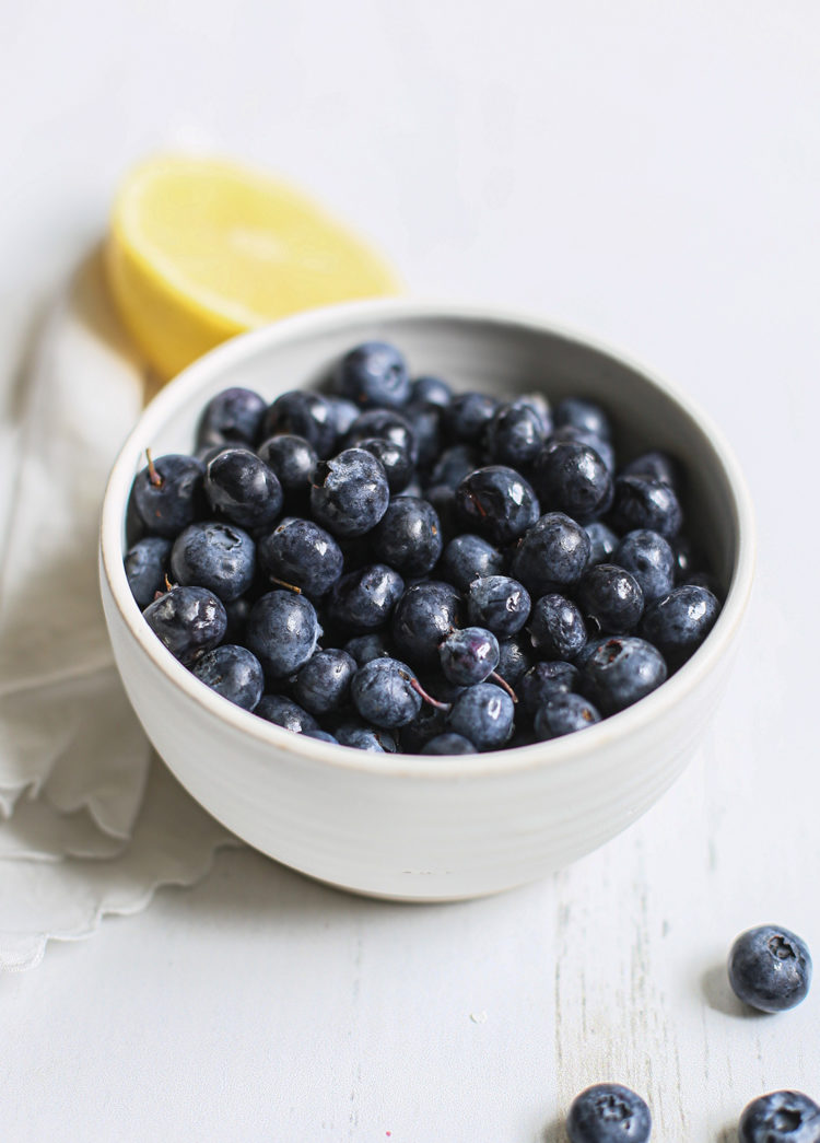 a bowl of fresh blueberries on a white wooden table before being frozen