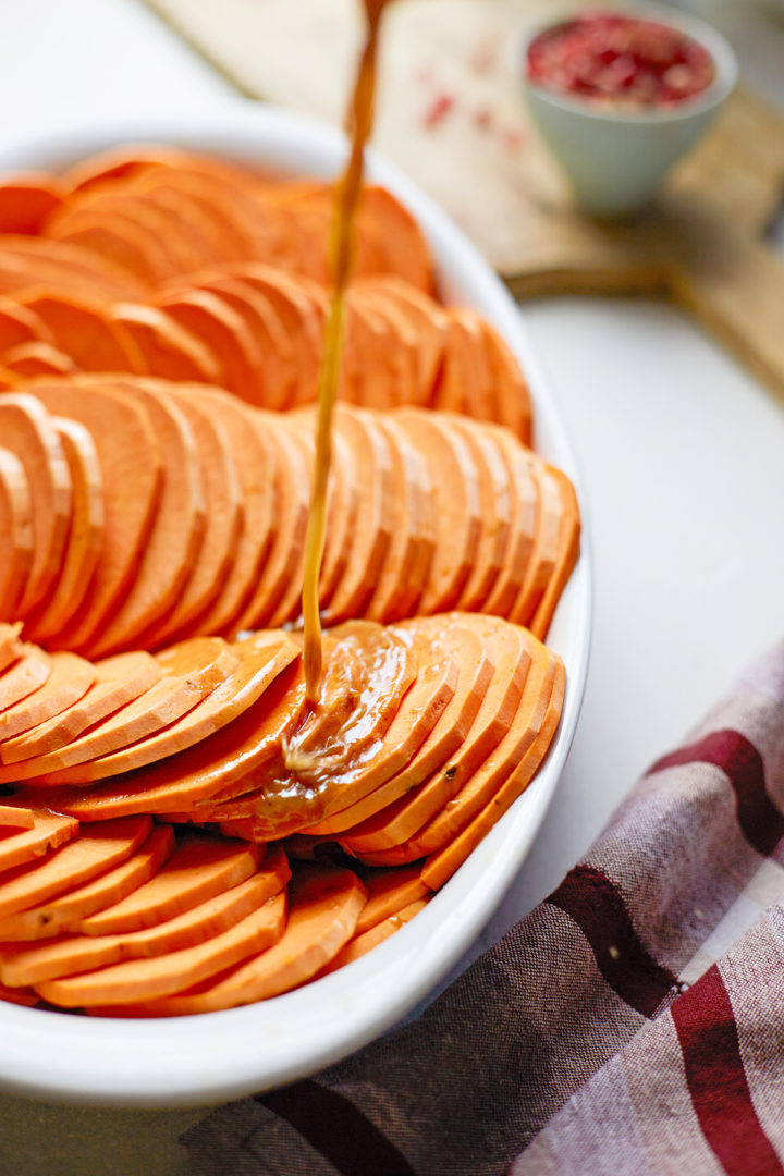 woman pouring glaze over sliced sweet potatoes