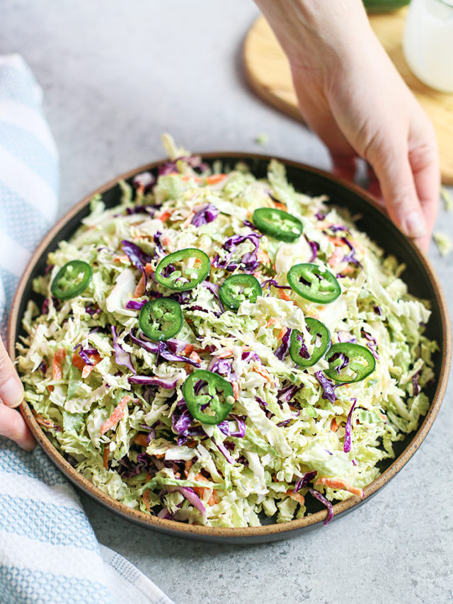 woman holding a bowl of jalapeño coleslaw