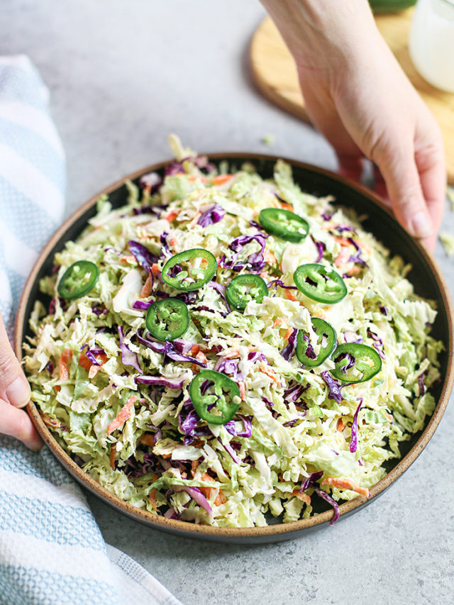 woman holding a bowl of jalapeño coleslaw