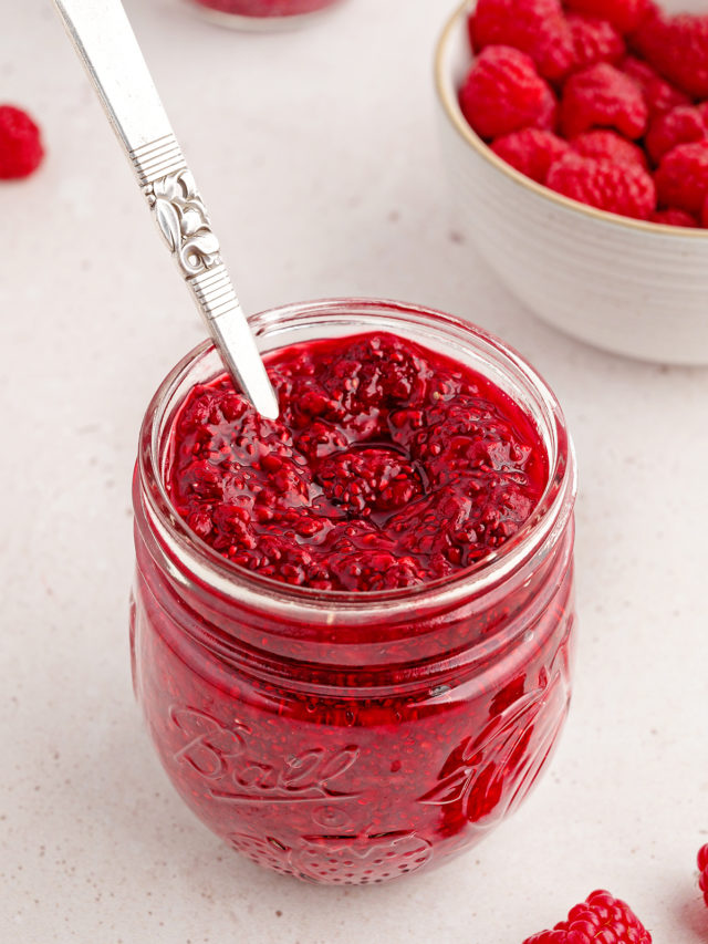 photo of chia jam for a recipe to make raspberry jam in a jam jar with a spoon and bowl of fresh raspberries