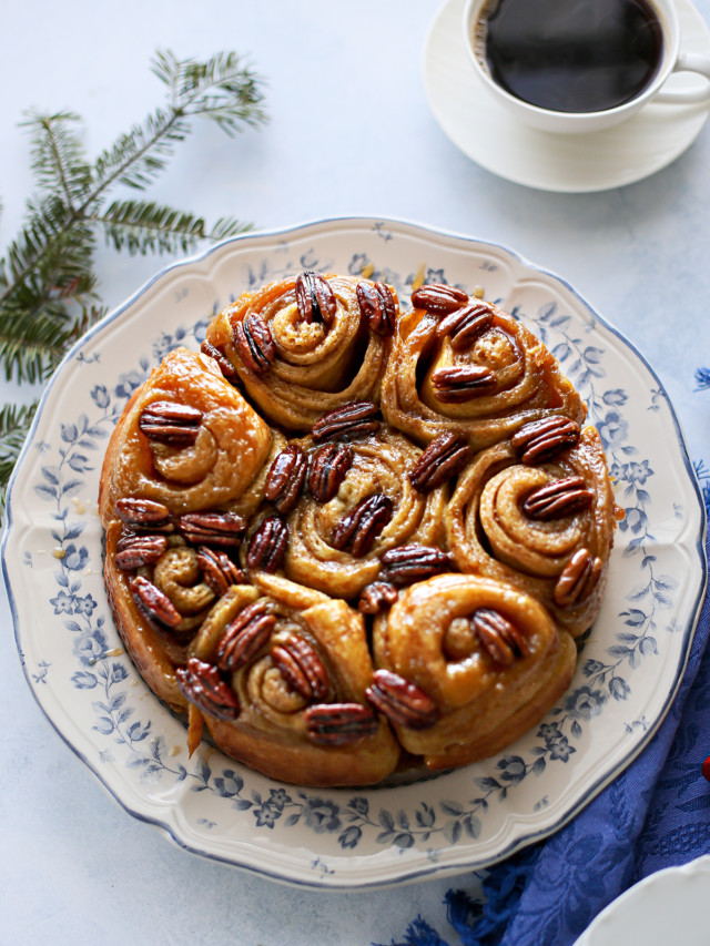 photo of pecan rolls on a plate set at a table next to a mug of coffee