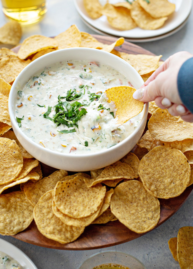 woman scooping queso blanco with a tortilla chip