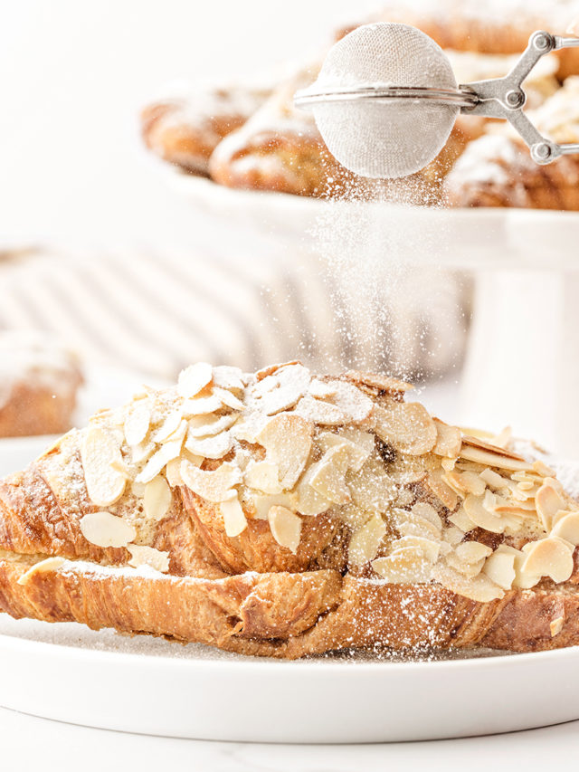 photo of this recipe for almond croissants being dusted with powdered sugar