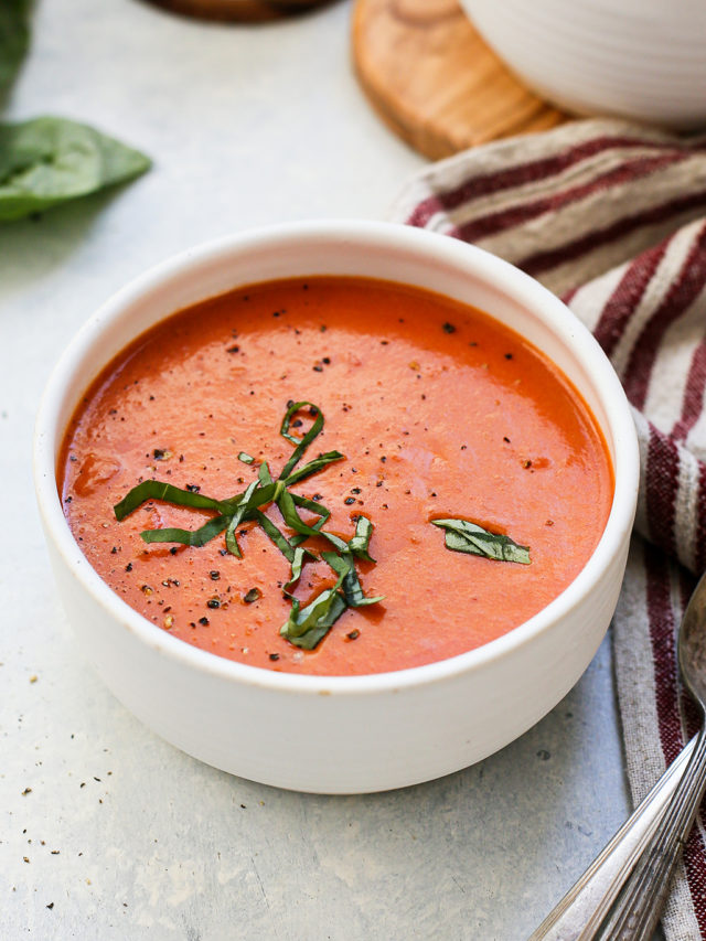 photo of a white bowl of cream of tomato soup on a light blue background