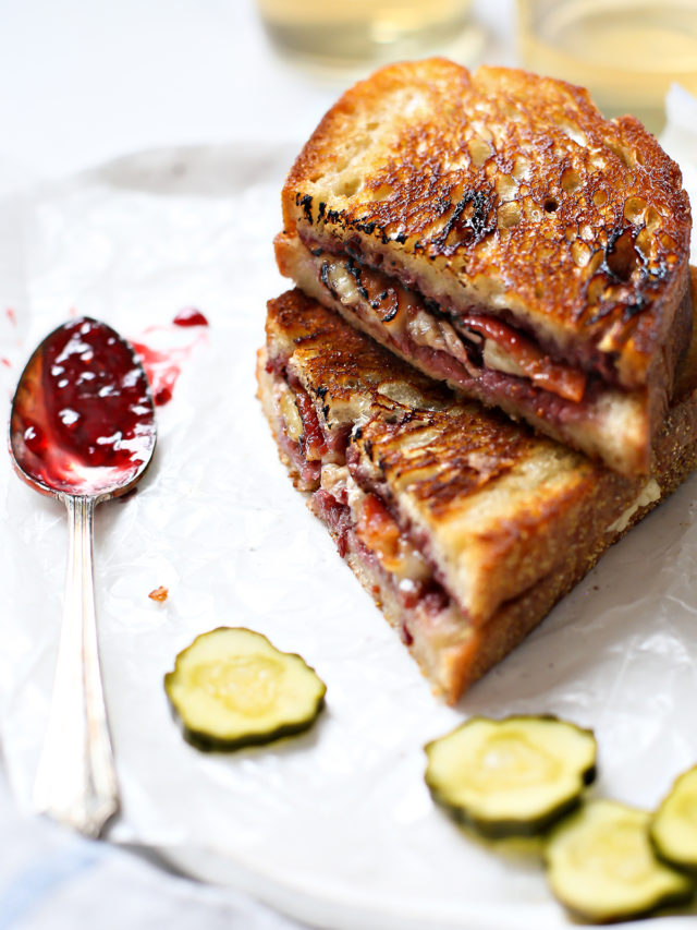 a brie grilled cheese cut in half and stacked next to pickle slices