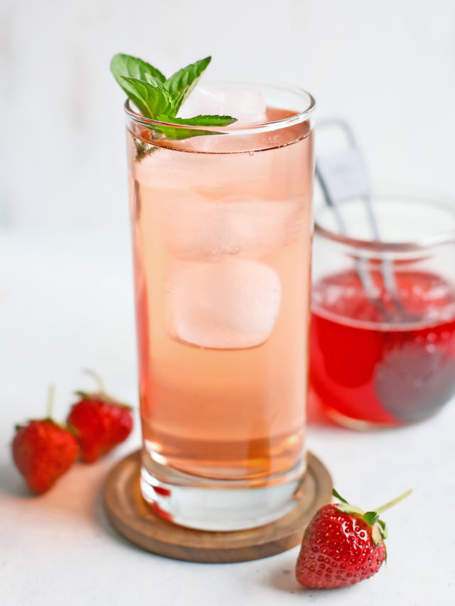 drink made with strawberry simple syrup served in a tall clear glass with a mint garnish