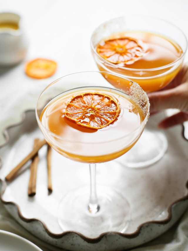 woman picking up a glass of pumpkin martini