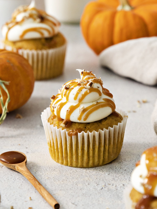 pumpkin cupcakes with cream cheese frosting on a light background with mini pumpkins