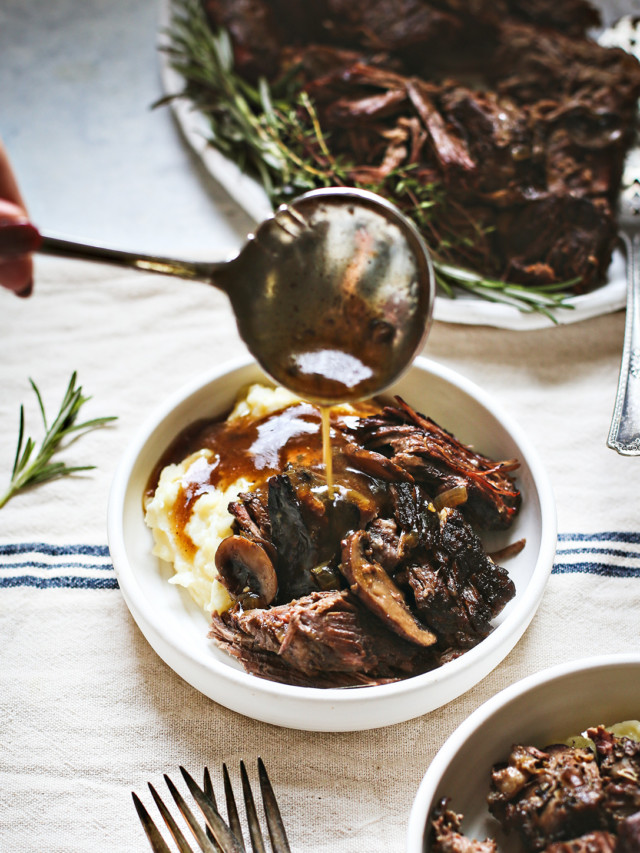 woman spooning mushroom gravy onto a bowl of Instant Pot chuck roast with mashed potatoes