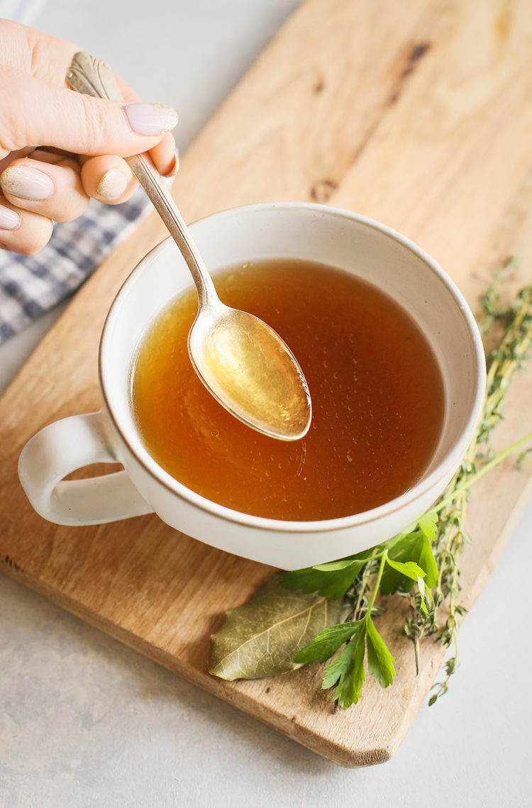 Instant Pot chicken stock in a white mug with a spoon