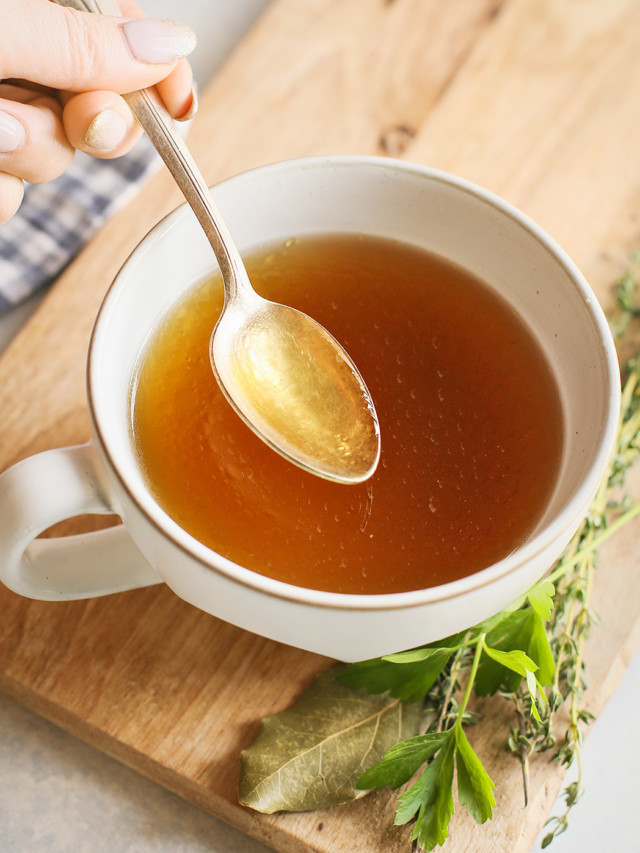 Instant Pot chicken stock in a white mug with a spoon