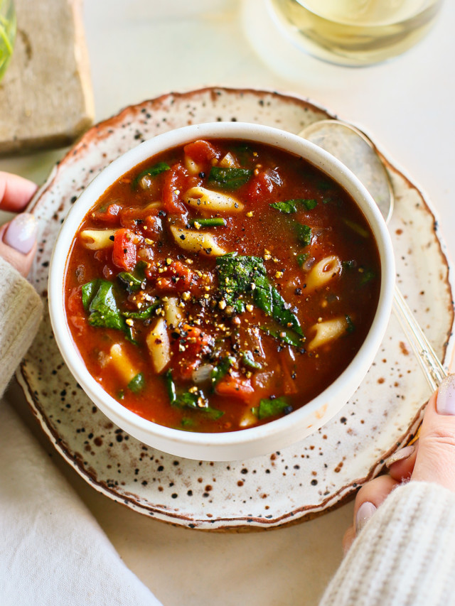 woman holding a bowl of tomato florentine soup