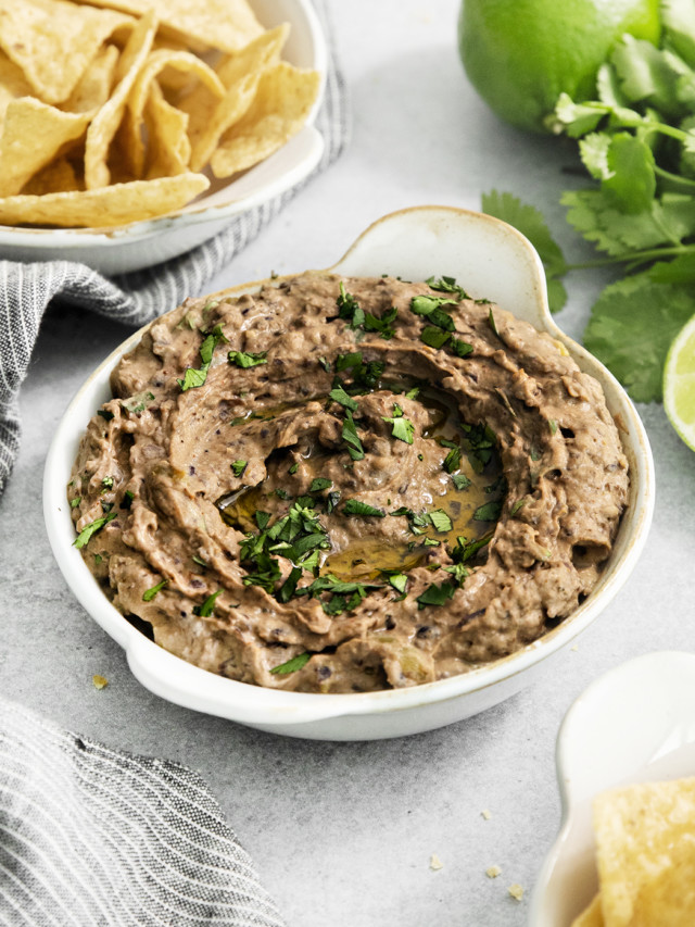 black bean hummus in a white dish next to tortilla chips