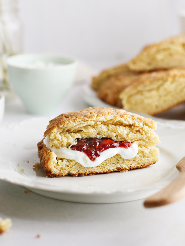 basic scone on a plate served with raspberry jam and a knife next to a plate of fresh homemade scones