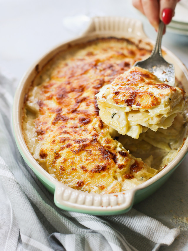 woman serving scalloped potatoes from a baking dish