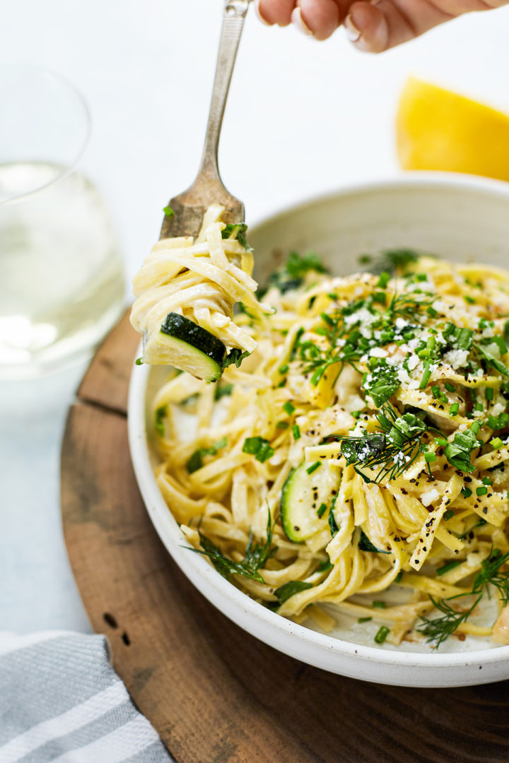 woman eating a bowl of creamy pasta primavera with chicken