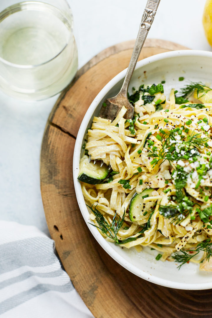 a bowl of pasta primavera with chicken with pasta twirled around a fork